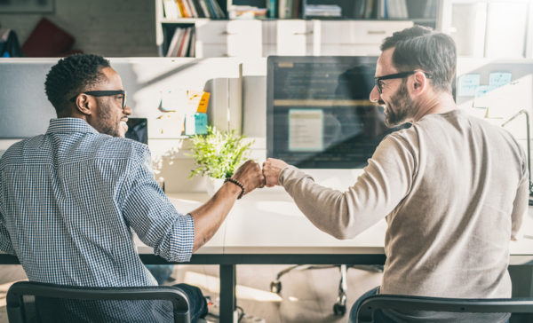 CRM VS ERP: What's the difference? Two guys fist bumping each other sitting down